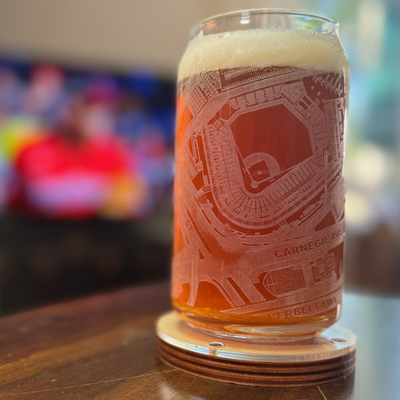 Glass of beer with a stadium etching on a coaster, blurred background
